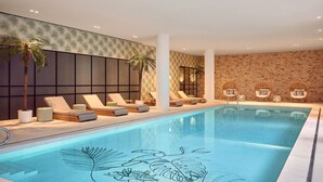 A swimming pool with lounge chairs and palm trees, surrounded by a brick wall and a patterned wallpaper. - Van der Valk Hotel Lelystad (Lelystad)