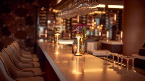 A bar area with a row of chairs, a candle, and a vase with a flower. - Van der Valk Hotel Lelystad (Lelystad)