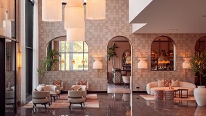 A spacious lobby with a modern design, featuring a seating area with sofas and armchairs, a bar area, and large windows allowing natural light. - Van der Valk Hotel Lelystad (Lelystad)