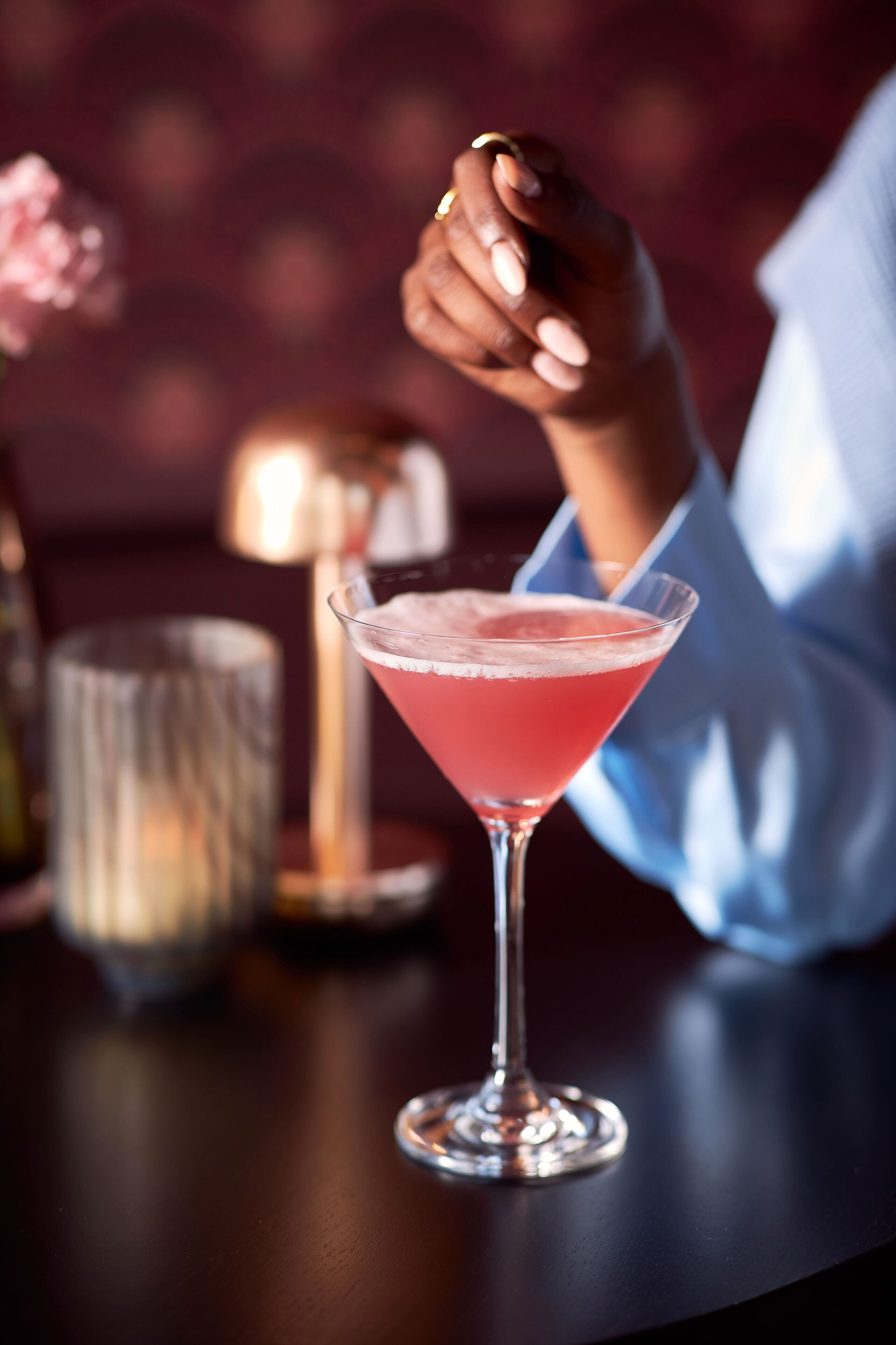 Ein Cocktail in einem Martiniglas auf einem Tisch, unscharfer Hintergrund.