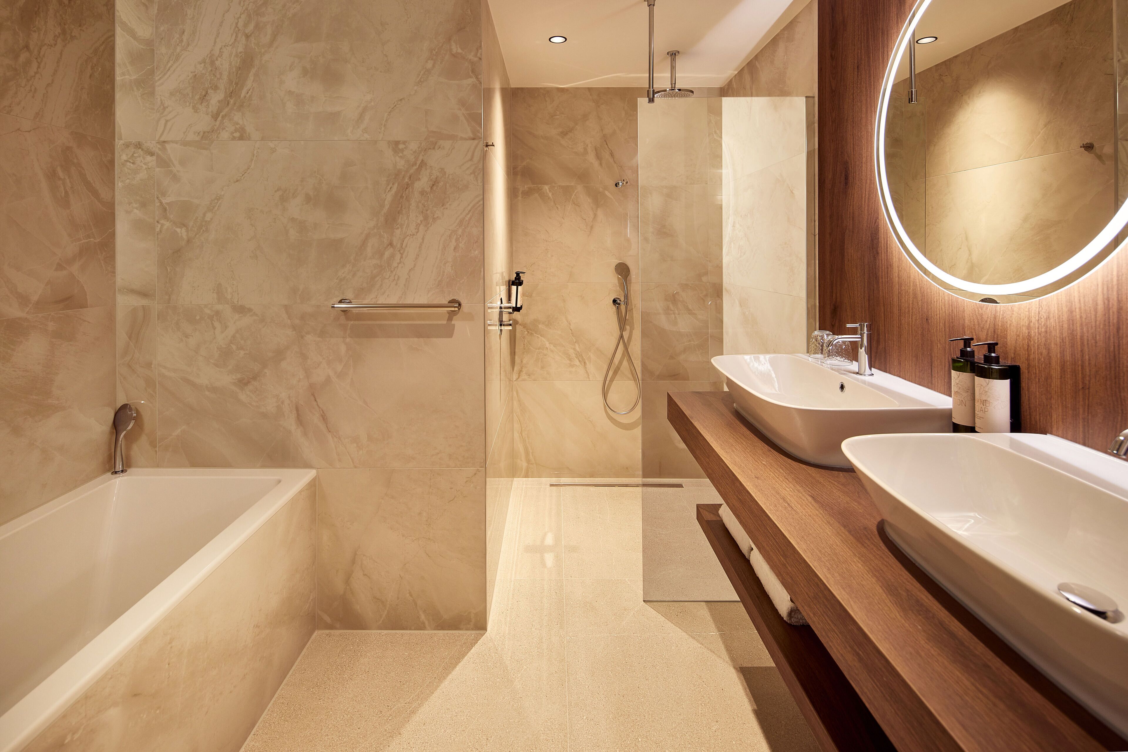 Un baño moderno con cabina de ducha, dos lavabos y un espejo grande.