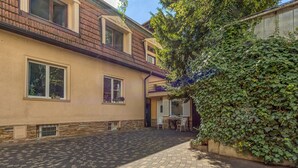 Un edificio con un cortile lastricato, una zona salotto all'aperto coperta e un muro ricoperto d'edera.