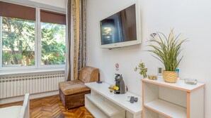 Un soggiorno moderno con un divano, un tavolino, una TV e una finestra con tende.