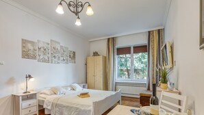 Camera da letto con letto, comodino, lampada, armadio, finestra con tende e angolo pranzo con tavolo apparecchiato per due.
