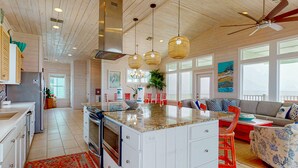 Una cocina amplia con una isla grande, techo de madera e iluminación colgante.