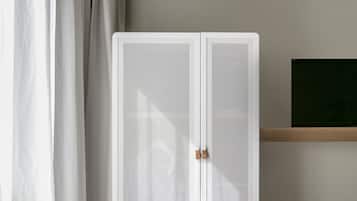 A bedroom with a bed, a wardrobe, a handbag, and a window with curtains.