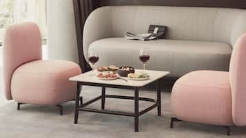 A modern living room with a sofa, two armchairs, a coffee table, and a dining table set with food and drinks.