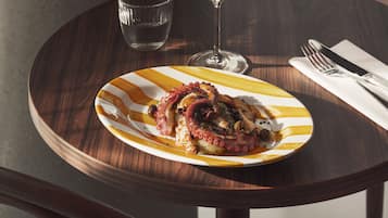 A wooden table with a plate of food, a glass of water, and a wine glass.