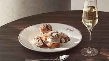 A dessert plate with ice cream and a glass of white wine on a wooden table.