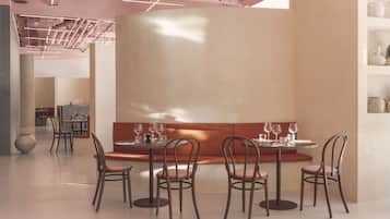 A modern interior with a round table, four chairs, and a bench. There are wine glasses on the table.