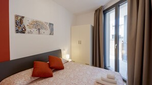 Una habitación de hotel con cama, un cuadro, un armario y una ventana con cortinas.