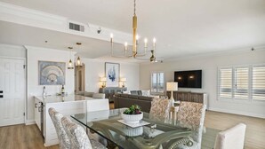 A spacious living area with a glass dining table, comfortable seating, a modern chandelier, and a flat-screen TV. - 🌴 Beachfront Penthouse! Shore Elegance | 3BR | Destin Towers 151 ☀️ (Destin)