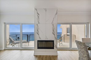 Un salon moderne doté d’une cheminée, de grandes portes-fenêtres coulissantes et d’une vue sur l’océan.