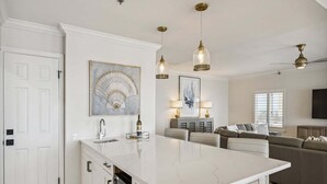 A modern kitchen with a marble island, pendant lights, and artwork on the walls. - 🌴 Beachfront Penthouse! Shore Elegance | 3BR | Destin Towers 151 ☀️ (Destin)
