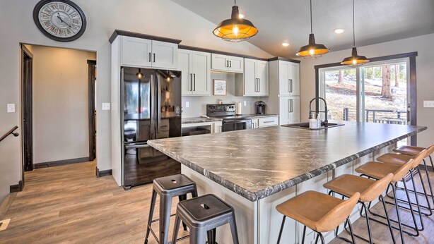 A modern kitchen with a large island, bar stools, and pendant lighting. - Modern Lead Cabin w/ Private Hot Tub & Fireplace! (Lead)