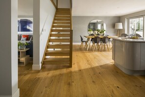 Eine moderne Küche mit einer Holztreppe, einem Essbereich und einer Kücheninsel.
