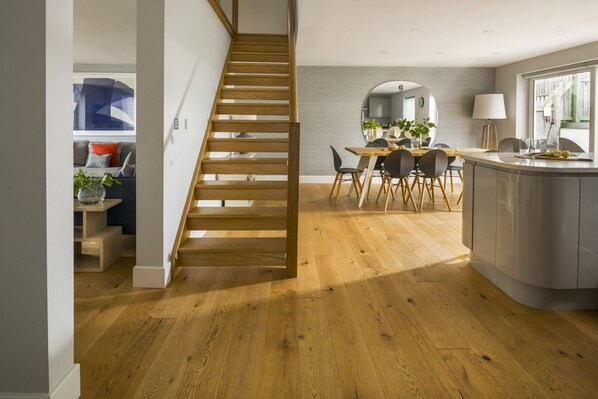 A modern kitchen with a wooden staircase, a dining area, and a kitchen island.
