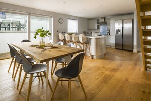 Eine moderne Küche mit einer zentralen Kochinsel, Edelstahlgeräten und einem Essbereich mit Holztisch und Stühlen.
