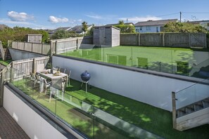 Eine moderne Außenpatio mit Glasgeländer, einem Grill und einem Esstisch für zwei Personen.