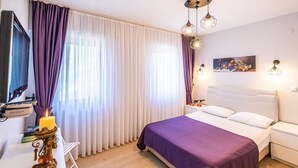 Un dormitorio con una cama, una mesita de noche, un televisor y un escritorio con una lámpara.