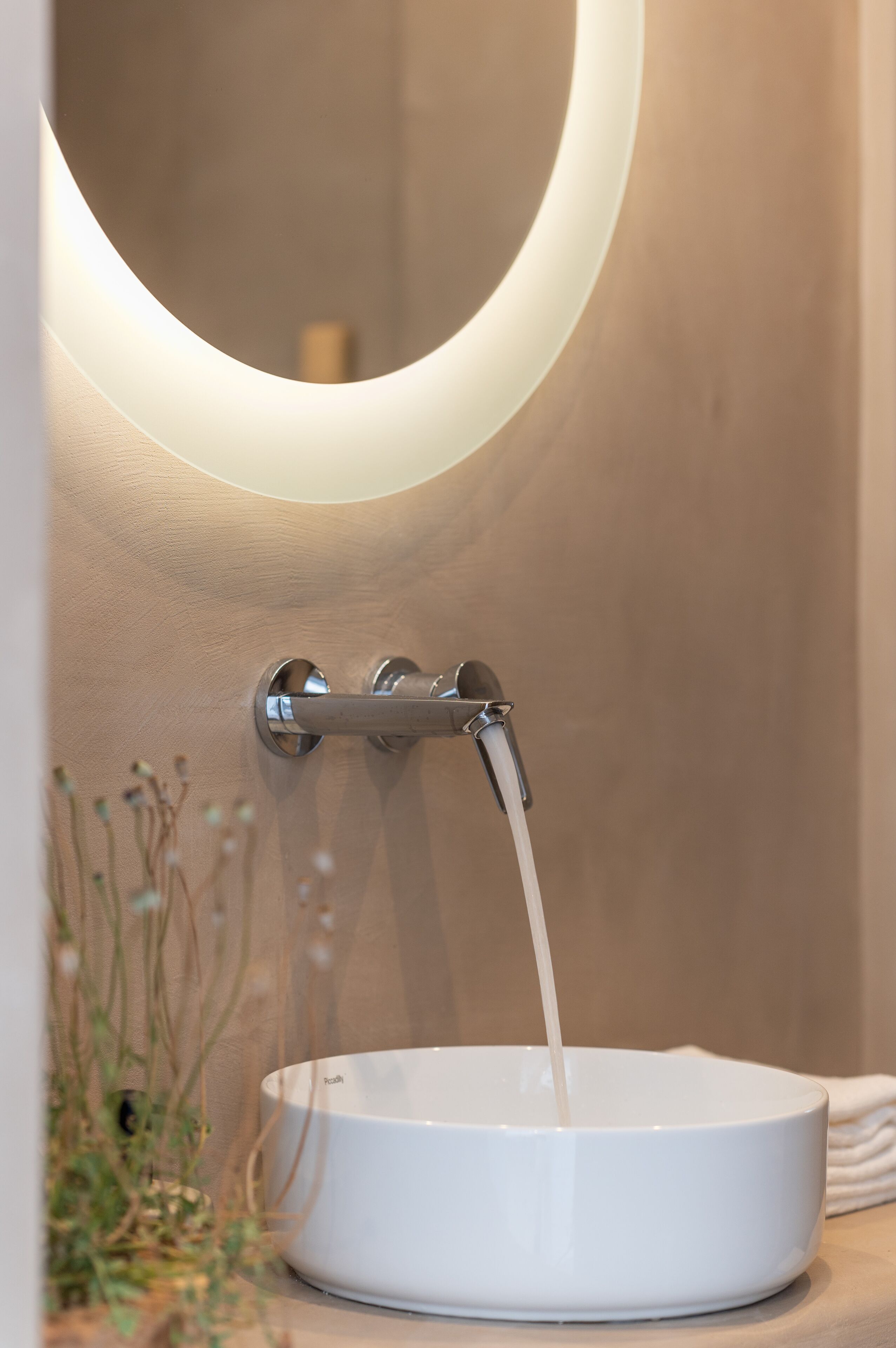 A bathroom with a modern design, featuring a white sink with a faucet and a mirror above it.
