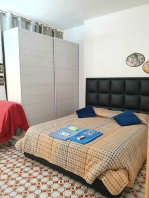 A bedroom with a bed, a wardrobe, and a patterned floor. - THE HOME OF THE JUNIOR BRATS  (Matera)