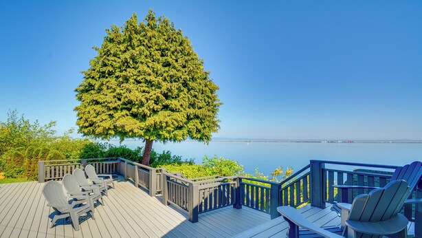 A wooden deck with Adirondack chairs and a view of the water. - Chic Port Angeles Home w/ Oceanfront Balcony! (Port Angeles)