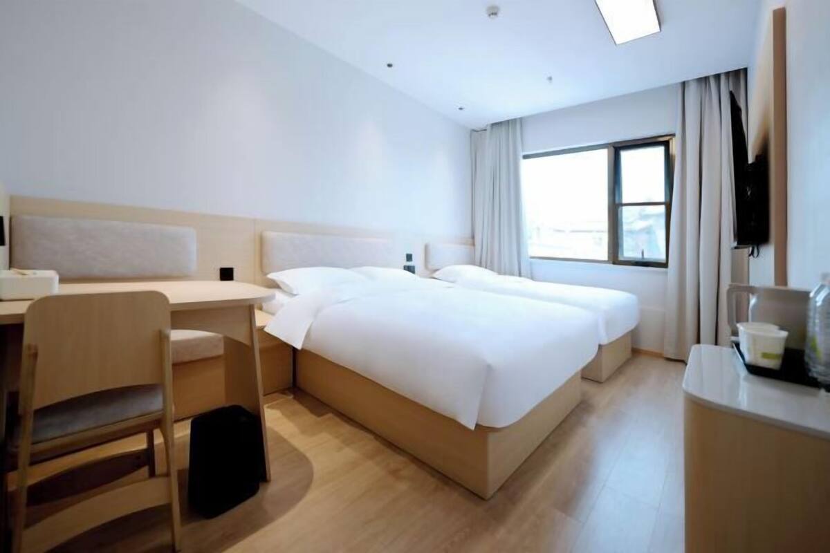 Habitación de hotel con cama, escritorio, silla y televisor.
