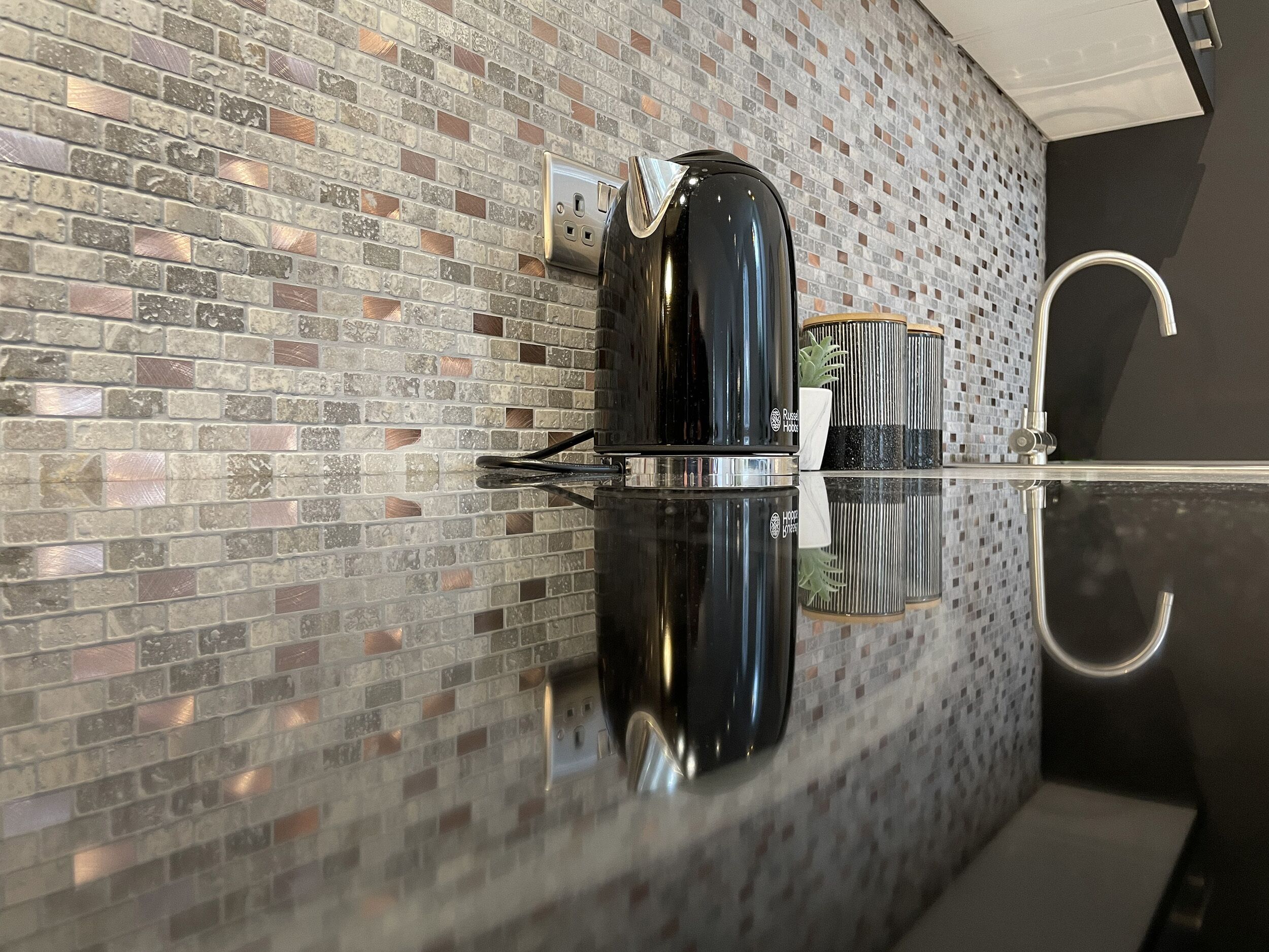 A modern kitchen with a reflective backsplash, stainless steel appliances, and a minimalist design.