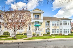 A multi-story residential building with a central entrance, a covered porch, and a well-maintained lawn.