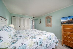 A bedroom with a bed, a dresser, a television, and a closet.