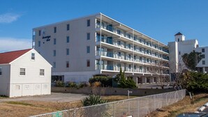 Un hotel de varios pisos con fachada blanca, balcones y una pequeña estructura en forma de torre.