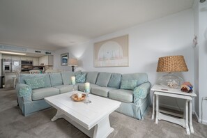 A living room with a light blue sofa, a white coffee table, and a small white side table with a lamp.