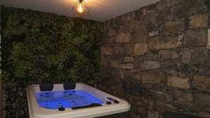 A hot tub with a stone wall and a green wall with plants. - Furnas Sweet Home - Central Zone (Furnas)
