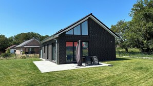 Een modern huis met een groot raam, een bakstenen gevel en een verzorgd gazon.