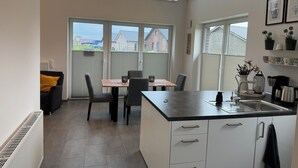 Een moderne keuken met een eethoek, grote ramen en uitzicht op de buurt.