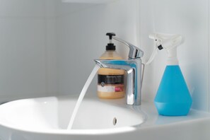 A bathroom sink with a chrome faucet and a blue spray bottle. - Athens Riviera Golf Apartment (Glyfada)