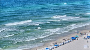 Una playa con olas, sombrillas y gente.