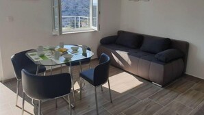 Una sala pequeña con un sofá y una mesa de comedor con sillas. Se ve una ventana con vistas a un paisaje montañoso.
