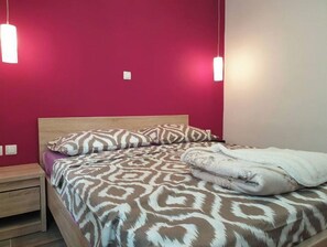 A bedroom with a bed, a nightstand, and two pendant lights.
