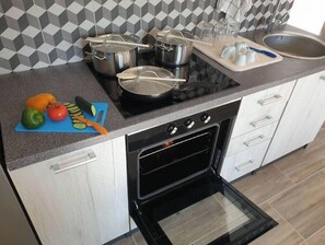 A modern kitchen with a gas stove, oven, and a blue cutting board with vegetables.