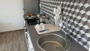 Una cocina moderna con un lavamanos de acero inoxidable, una encimera negra y un salpicadero con diseño.