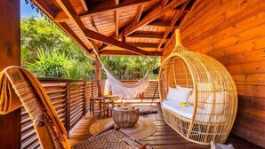 Un pontile in legno con un'amaca, sedie in vimini e un letto in vimini.