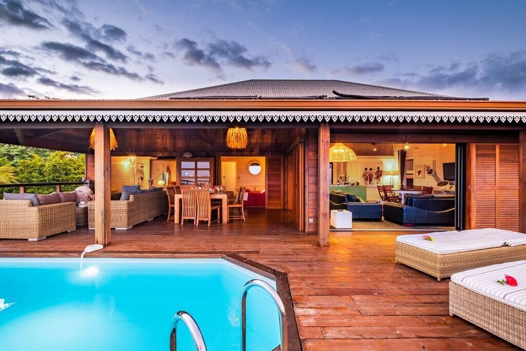 Une villa en bois dotée d’une piscine, d’un espace salon extérieur et d’un coin repas.