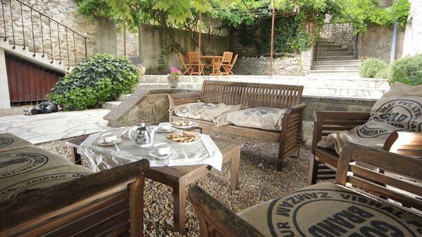 An outdoor seating area with wooden furniture and a table set for dining. - L'ESTAOU DE FINOU*** (Saint-Paul-et-Valmalle)