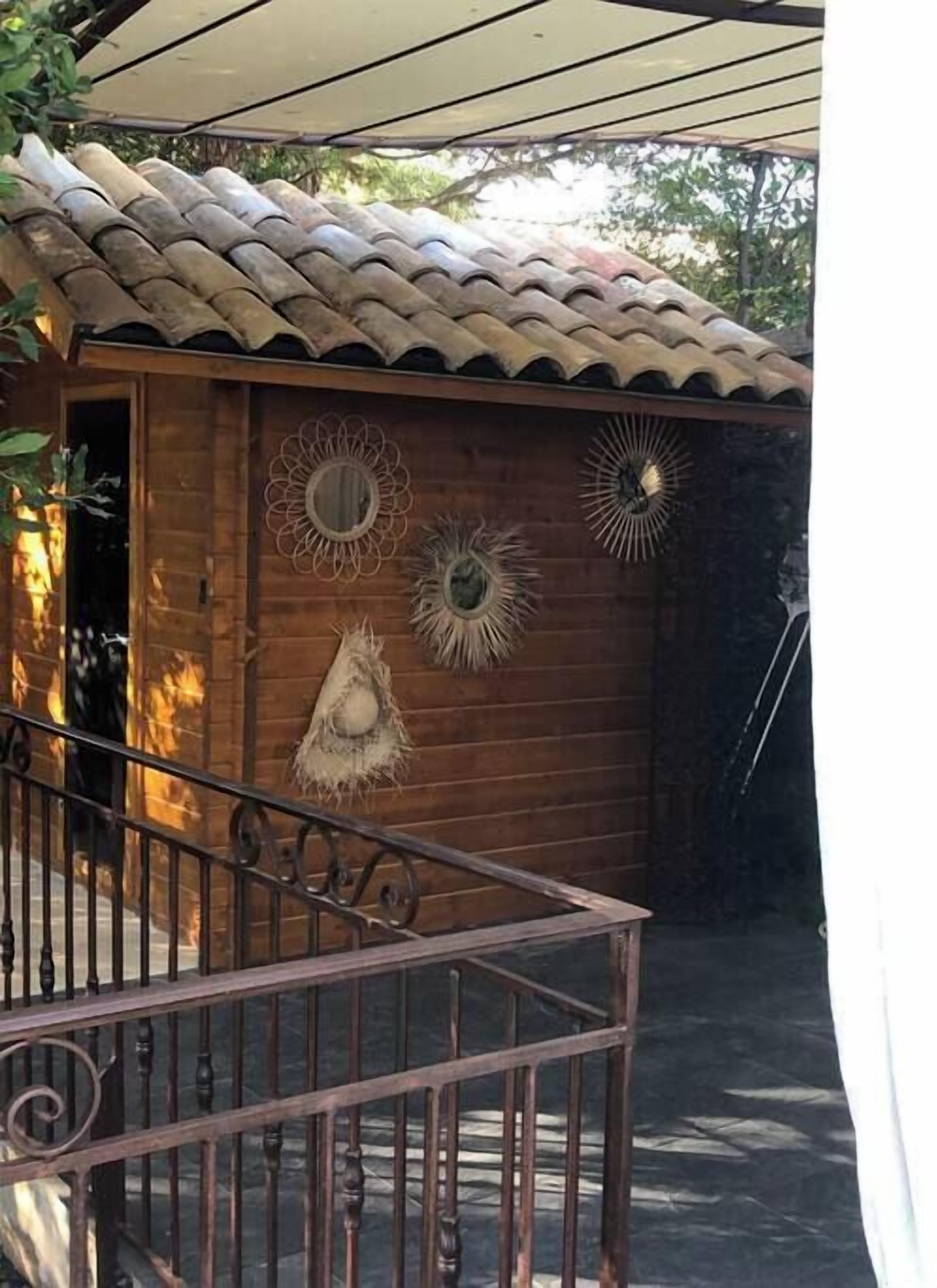 Ein Gebäude aus Holz mit einem Ziegeldach, einer Holztür und dekorativen Sonnenspiegeln an der Wand.