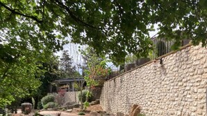 Ein geschwungener Holzweg in einem angelegten Garten mit Steinmauern und verschiedenen Pflanzen.