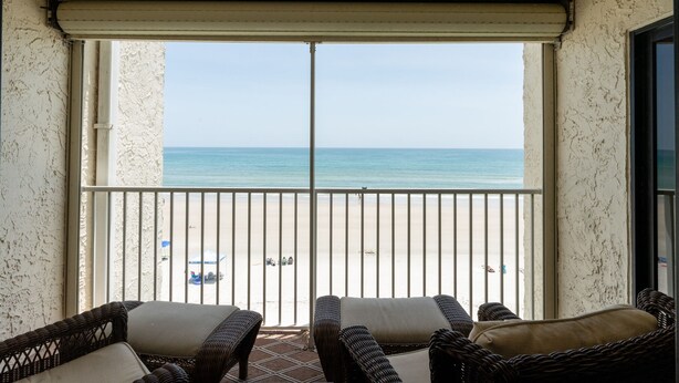 Ein Balkon mit Korbmöbeln und Blick auf den Strand.