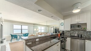 Eine moderne Küche mit Granit Arbeitsplatten, Edelstahlgeräten und Meerblick durch große Fenster.