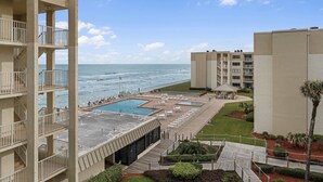 Ein Hotel mit Poolbereich, Sitzgelegenheiten im Freien und Blick auf das Meer.